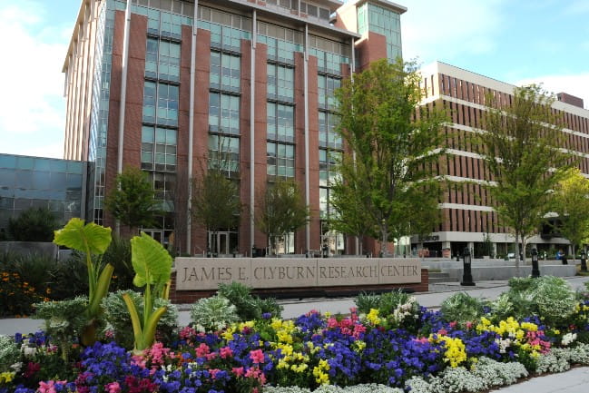 A flowerbed sits in front of a tall brick building and a sign that reads “James E. Clyburn Research center.