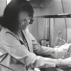 A woman in a lab coat operates instruments in a science lab.