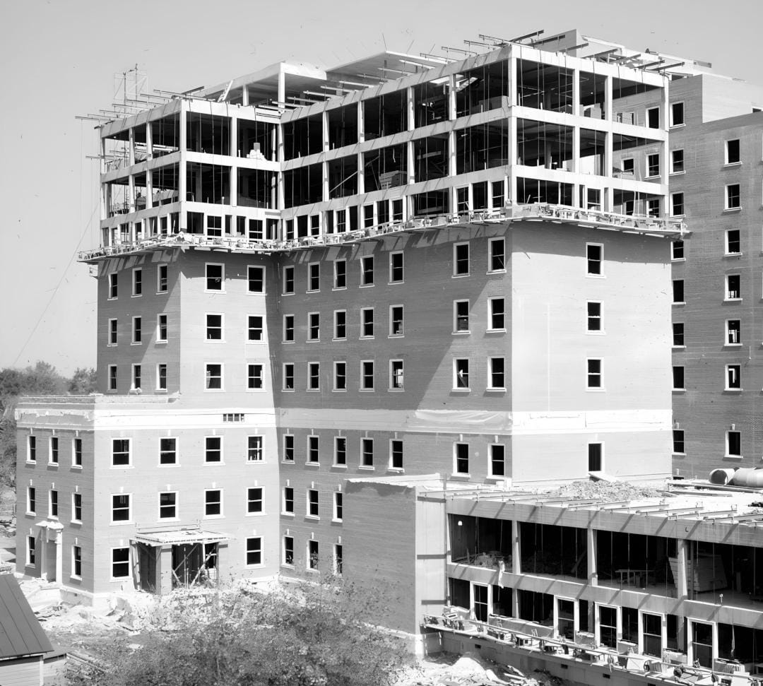 A building is under construction. The walls are complete, but windows have not been installed yet. The top three floors have only been framed, but lack walls.